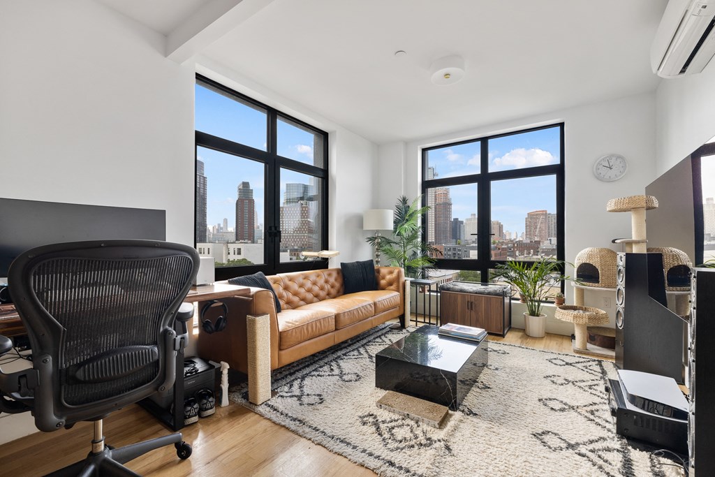 an open living room with a couch and a desk with a large window